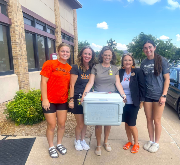 Five people standing in front of hospital with one person carrying a cooler