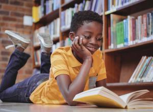 Child laying on the floor and reading a book