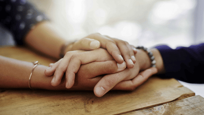 Two people holding hands in a reassuring embrace